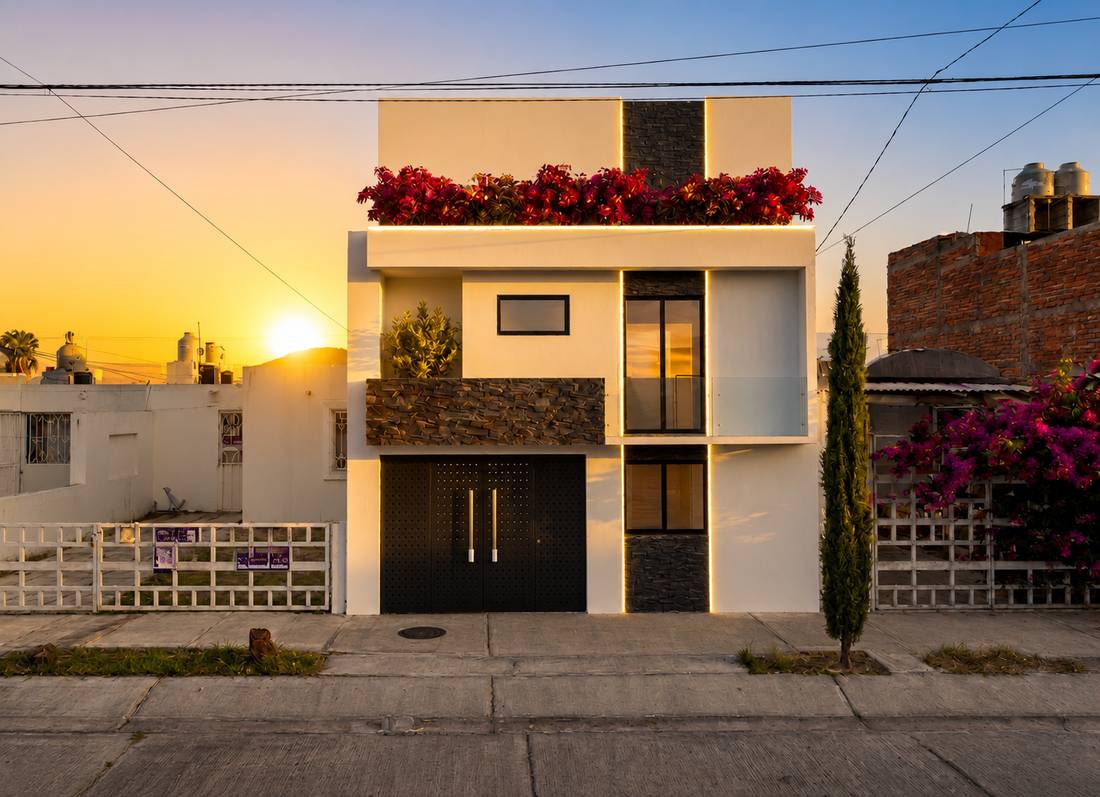 Casa blanca con acentos de piedra negra y bugambilias al atardecer